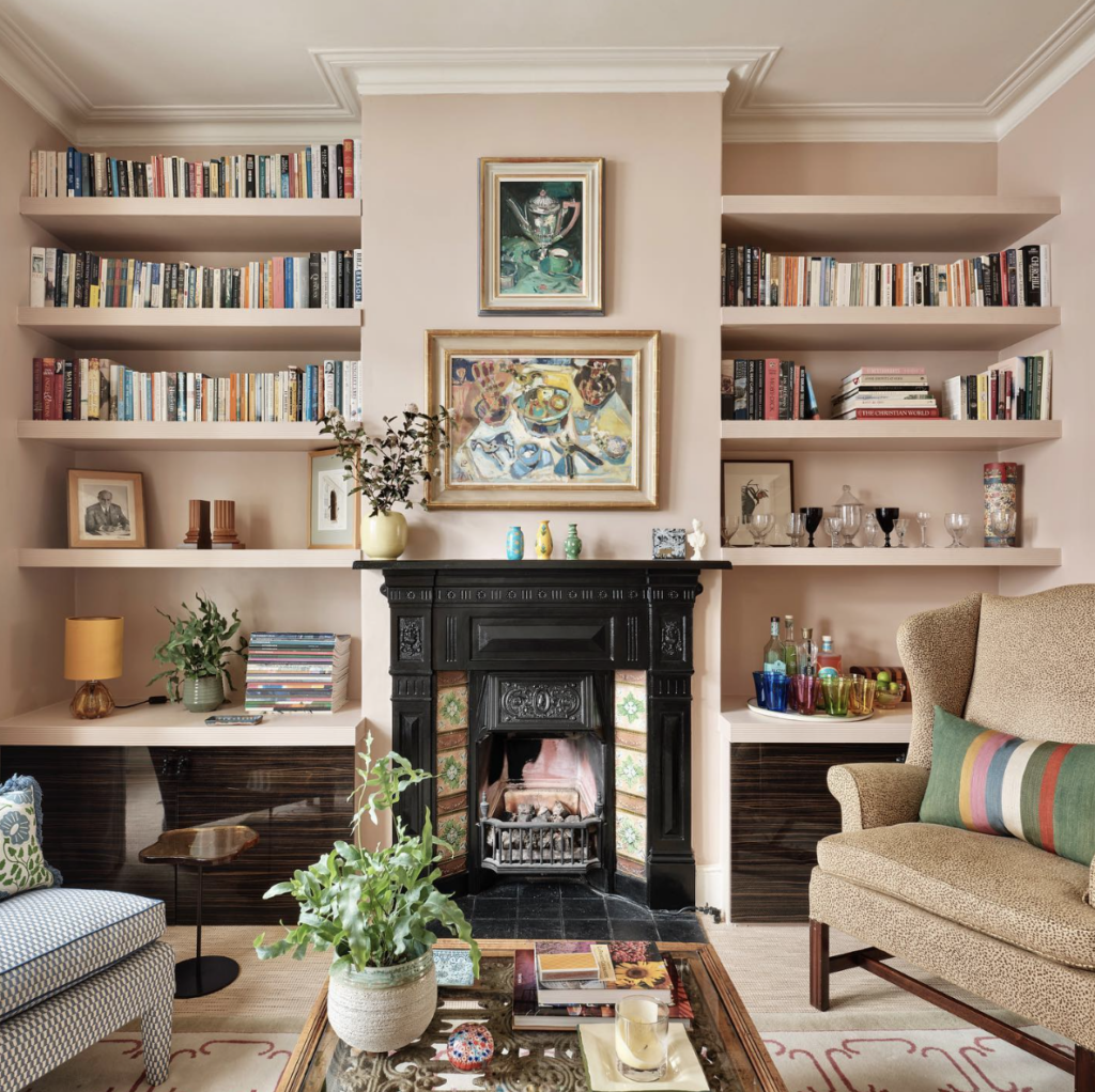 Pink Built-In Bookshelves On Both Sides Of Black Fireplace