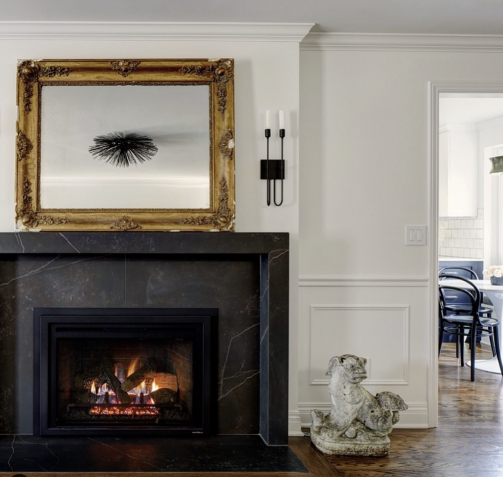 Gold Framed Mirror Over A Black Granite Fireplace Surround