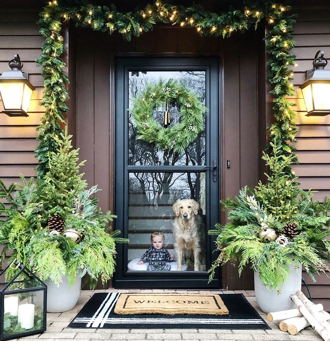 15. Natural Greenery and Warm Lighting for a Cozy Christmas Porch