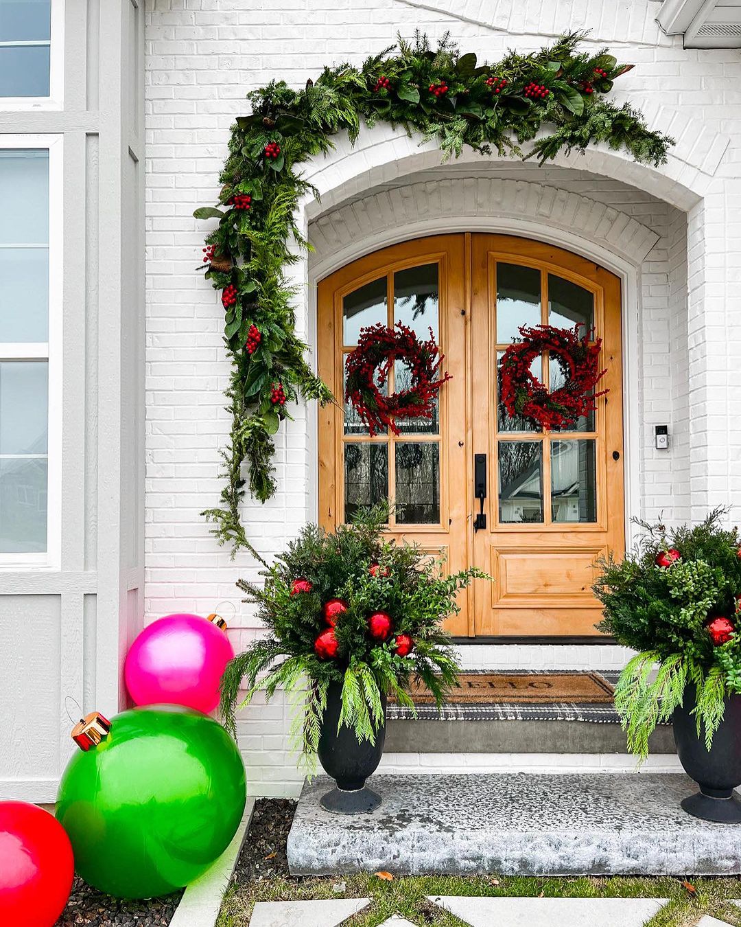 25. Bold and Playful Porch with Oversized Ornaments and Lush Greenery